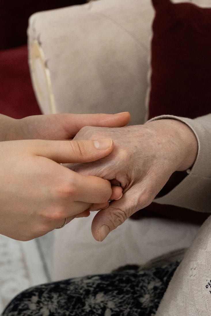 A caregiver gently holding a senior's hands during a home visit